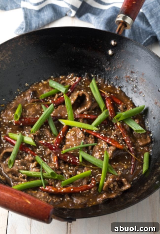 Szechuan beef stir-fry with added colorful vegetables like bell peppers and onions, cooking together in a pan for a balanced meal.