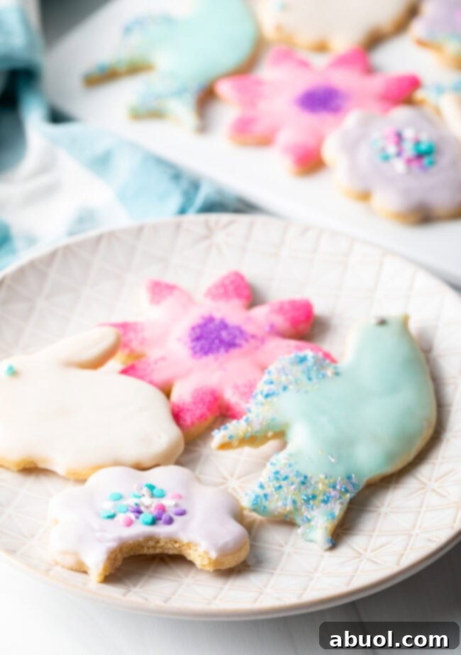 Beautifully iced sugar cookies in cheerful spring shapes arranged on a white plate, ready to be enjoyed.