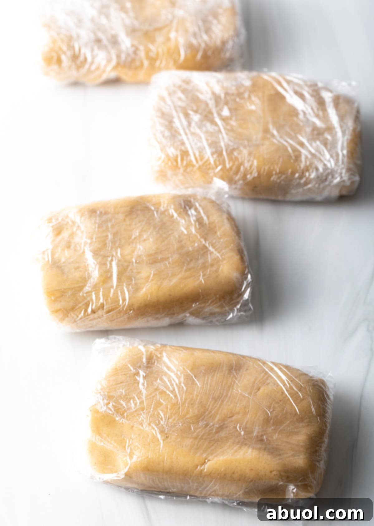 Cookie dough wrapped in plastic wrap, ready for chilling to achieve the perfect consistency for cut-out cookies.