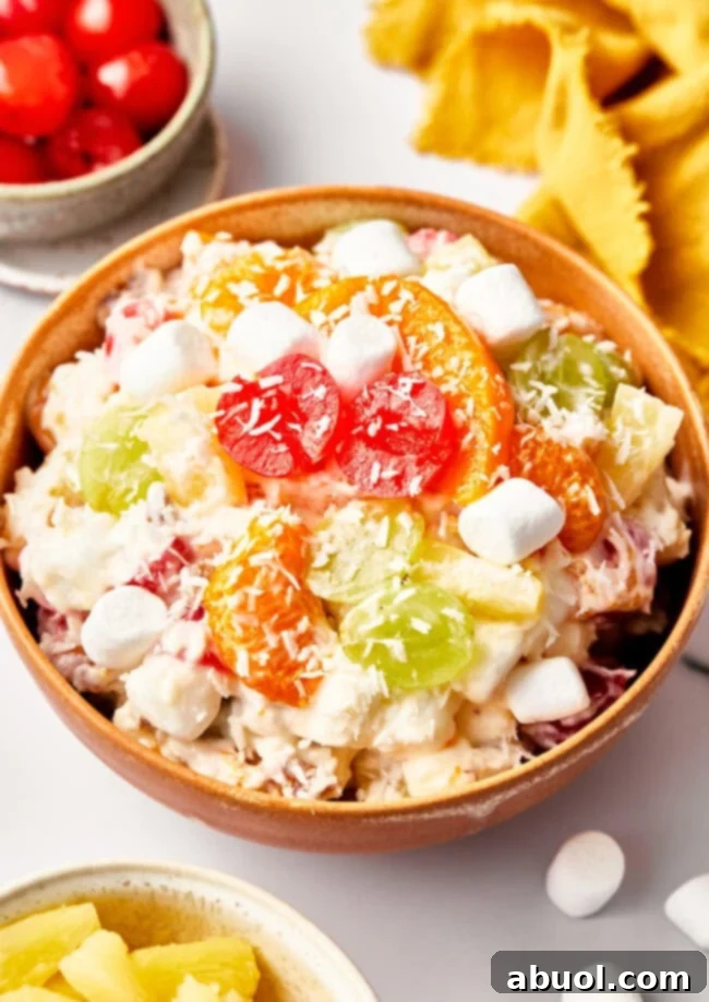An overhead view of the ambrosia salad in a bowl. Ingredients include marshmallows, cherries, grapes. 