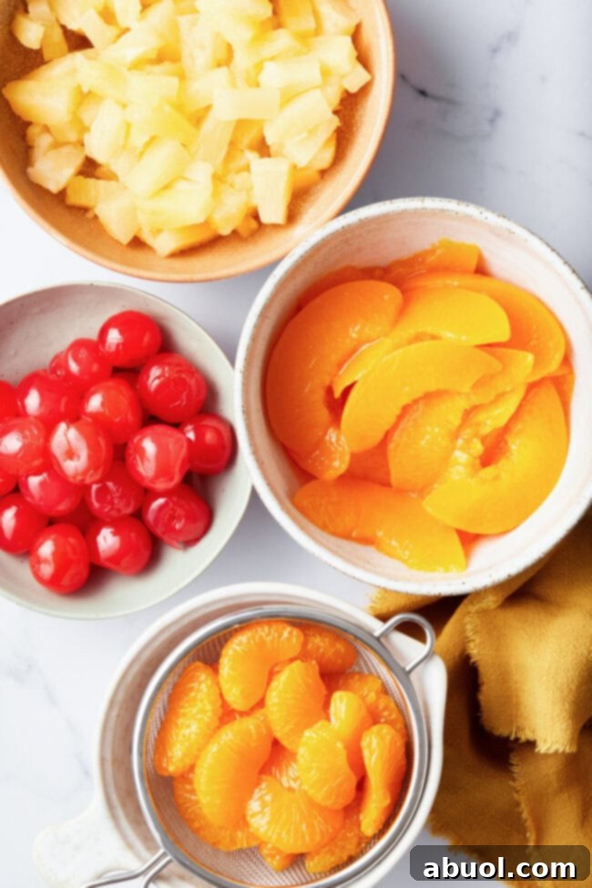 Overhead view of ingredients in individual bowls. You can see clementines, peaches, cherries and pineapple chunks. 