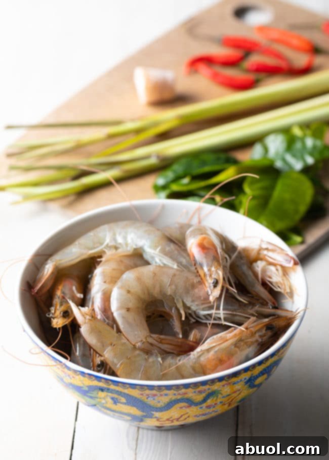Spicy Thai Tom Yum Perfection 5 Bowl of raw shrimp with other ingredients for soup in the background.