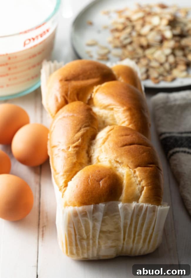 A fresh loaf of golden brioche bread, ready for slicing, emphasizing its rich texture.