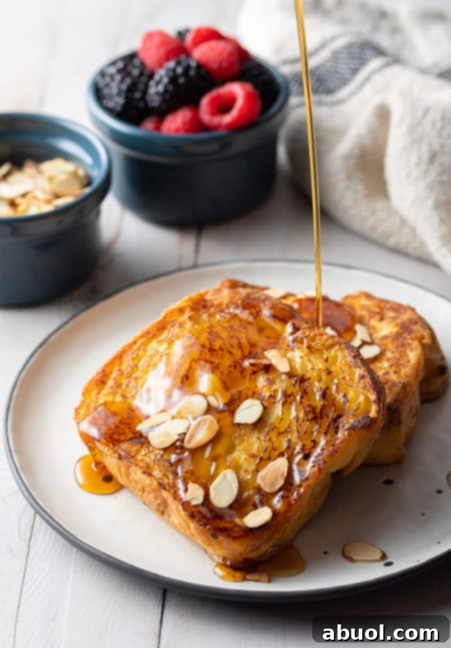 Two perfectly cooked slices of Pain Perdu drizzled with rich maple syrup, creating a tempting breakfast scene.