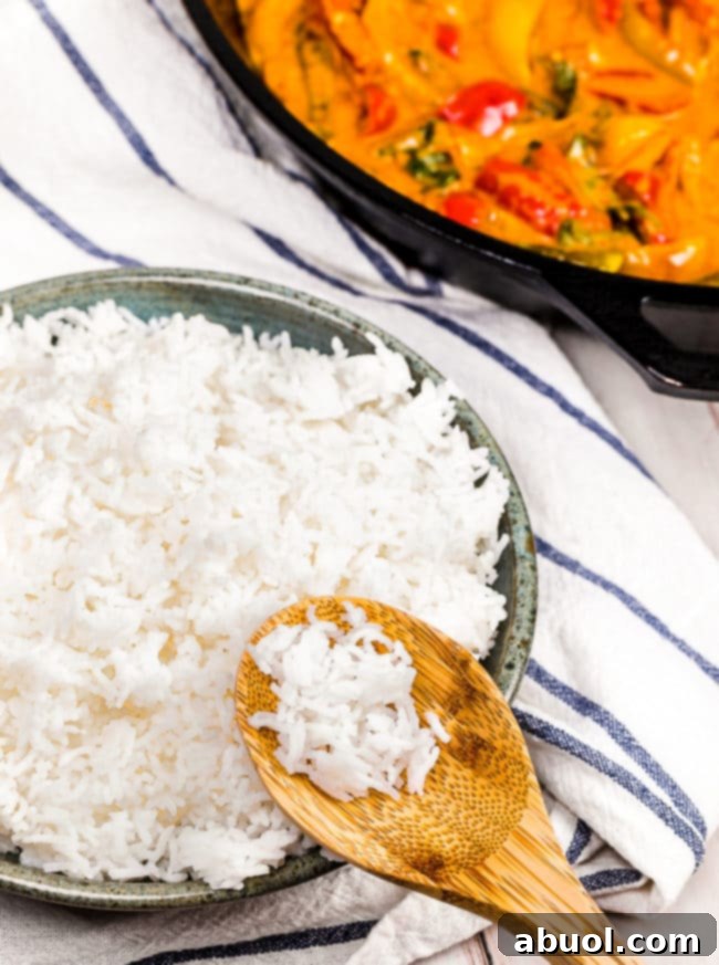 A wooden spoon delicately holding fluffy Basmati rice over a bowl, showcasing its light and separate grains.