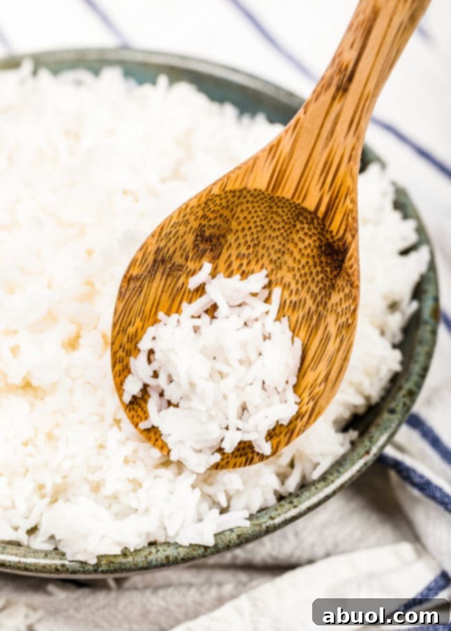 Close-up of uncooked Basmati rice in a sieve set over a bowl, highlighting the initial rinsing process for cooking.