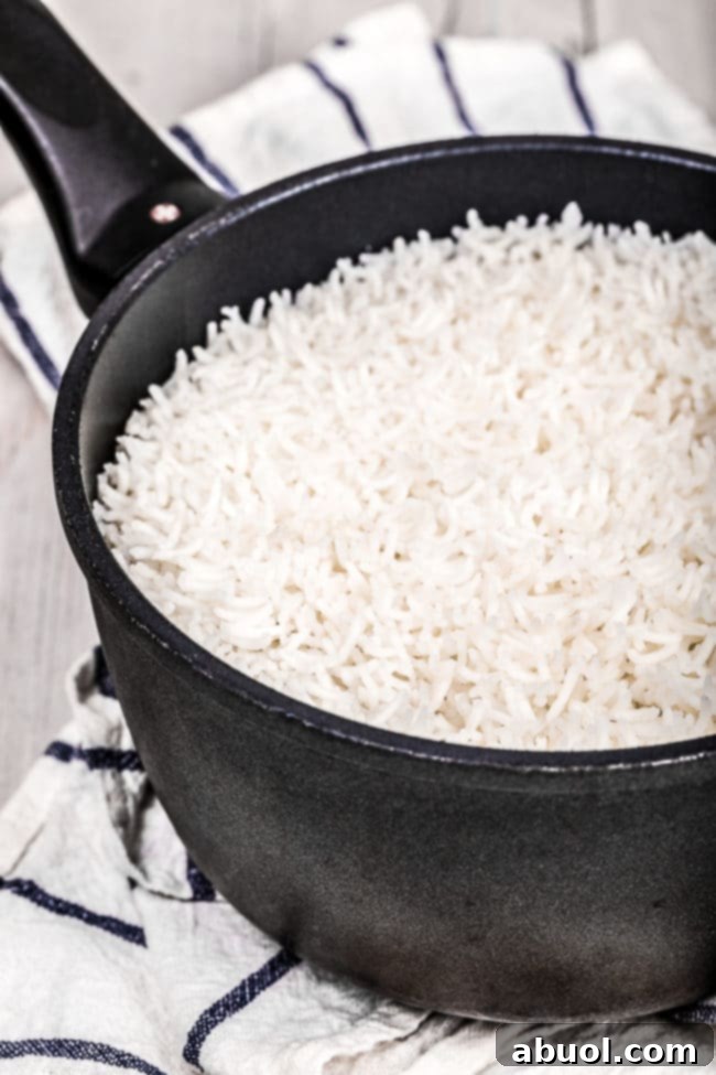 Close-up of Basmati rice cooking in a pot, showing the steam and texture before fluffing.