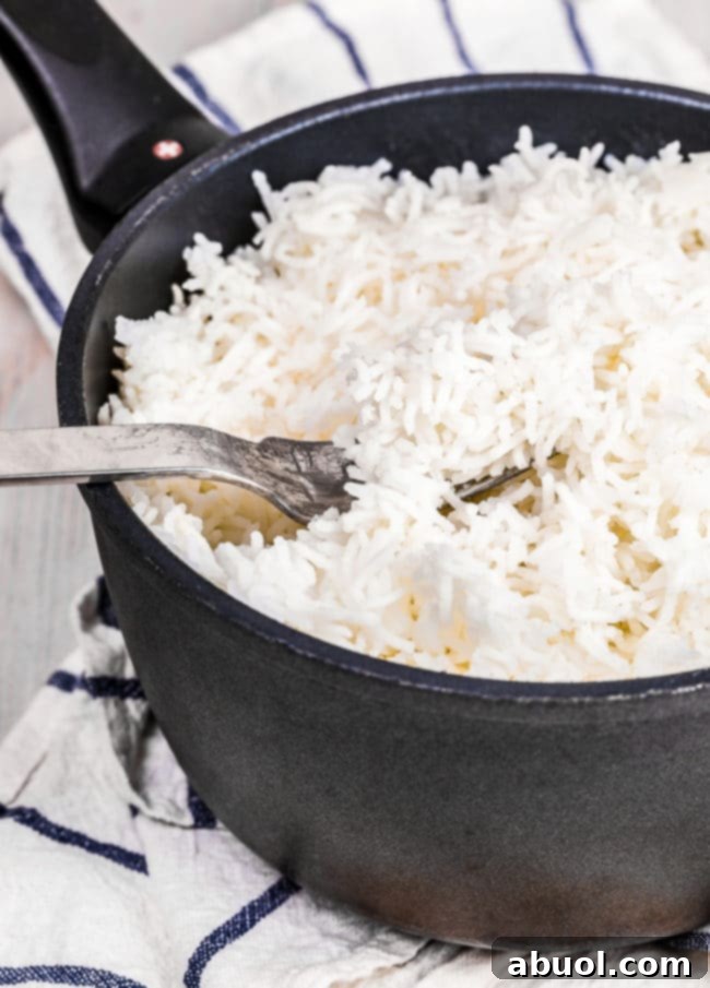 A fork fluffing warm, fluffy Basmati rice in a pot, showing the light, separated grains.