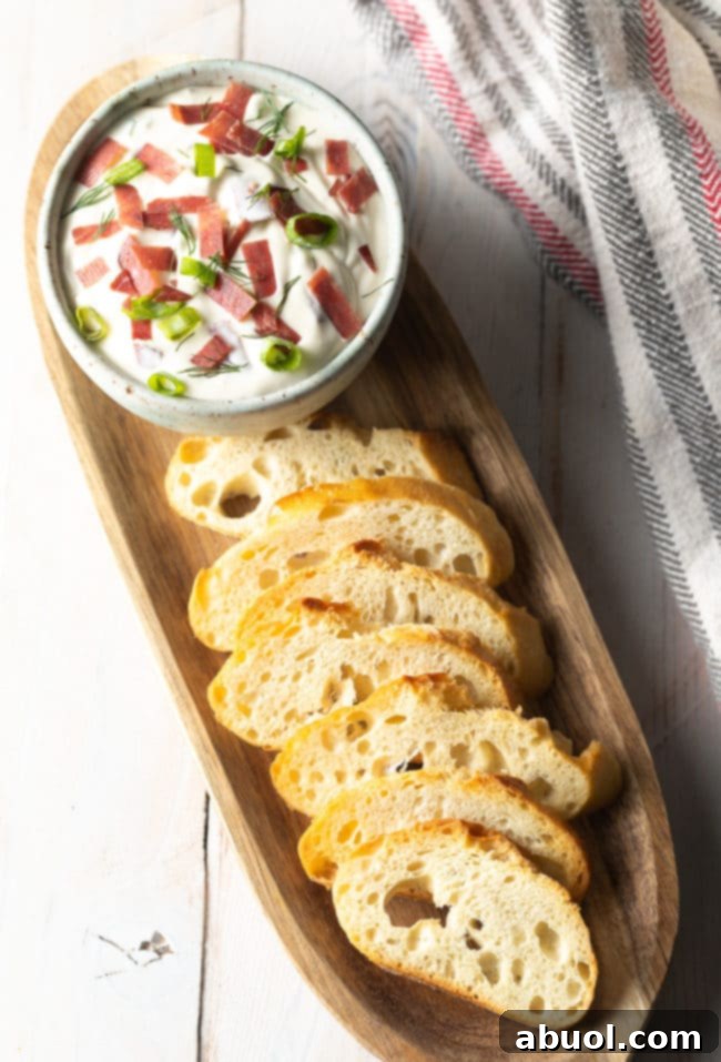 Platter of toasted crostini and a bowl of chipped beef dip, ready for serving.