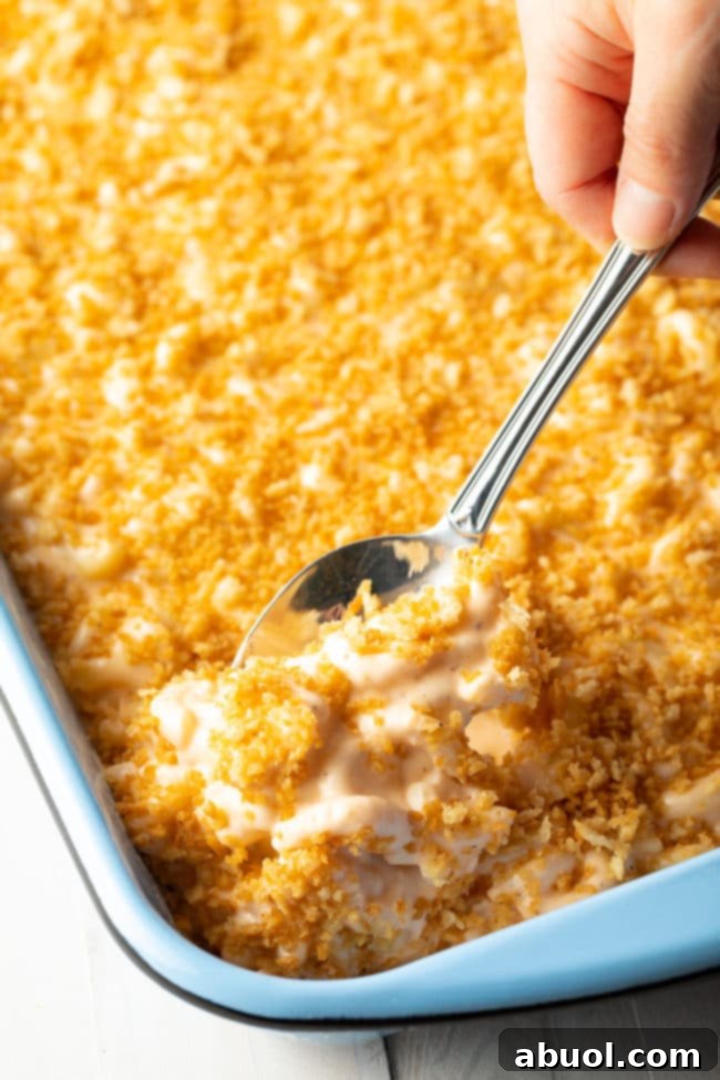 Homemade Mac and Cheese Perfection 13 Side view of baked macaroni with cream cheese in a casserole dish with a spoon taking out a portion