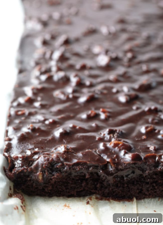 Texas Sheet Cake on a pan lined with parchment paper with part of the cake cut into.