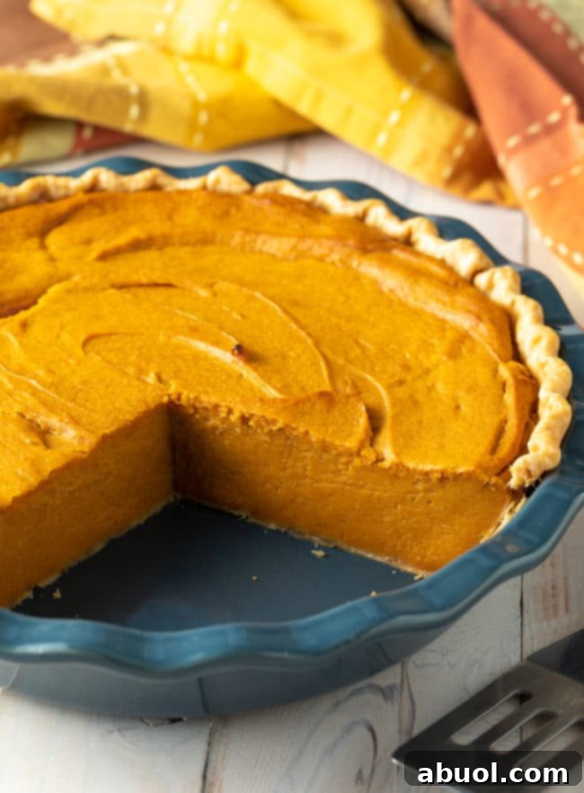 A whole, easy-to-make sweet potato pie with a few slices already cut out, showcasing its inviting golden-brown crust and smooth filling.