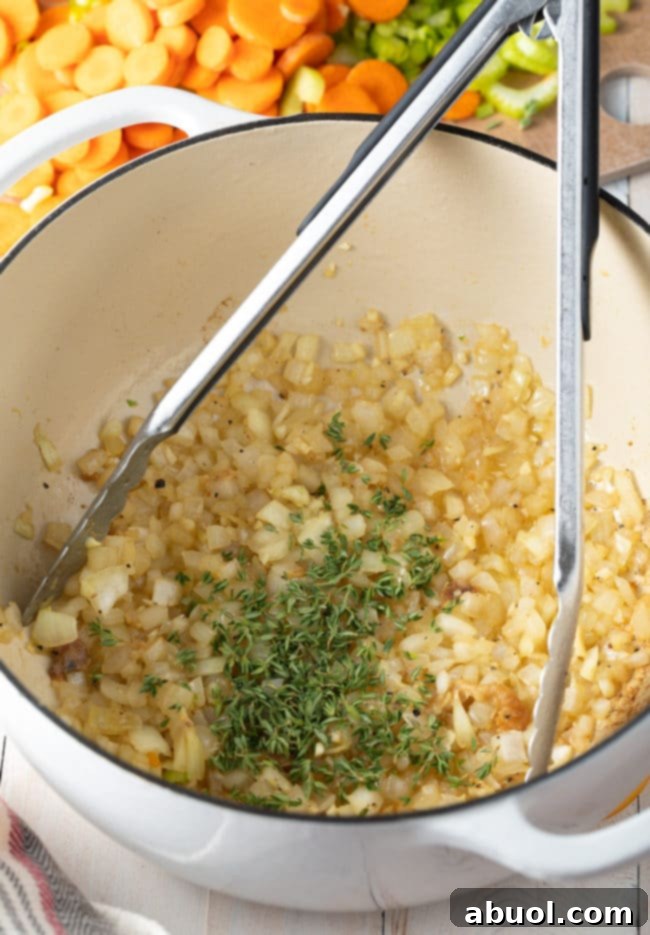 Onions, garlic, and fresh thyme cooking in a large pot, filling the kitchen with fragrant aromas.