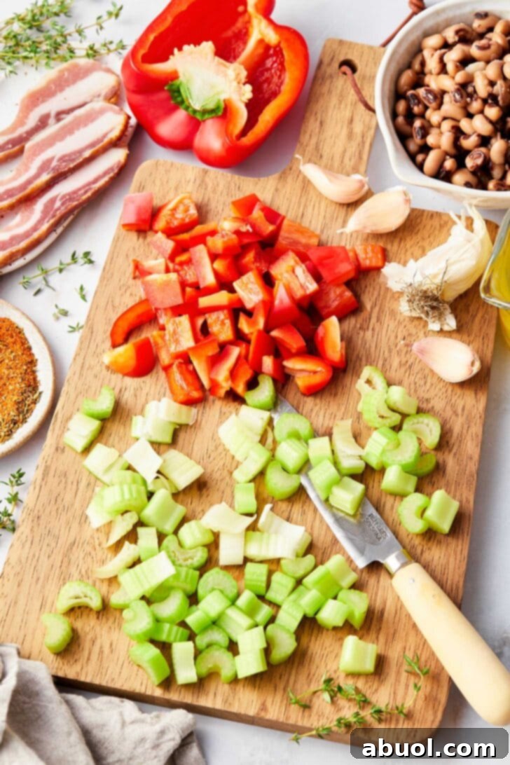 Overhead view of chopped celery, bell peppers, garlic and bowl of black eyes peas. 