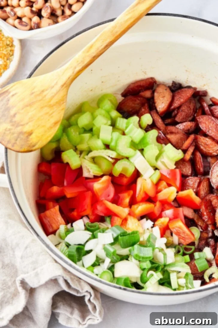 Vegetables being sauteéd in skillet with sausage.