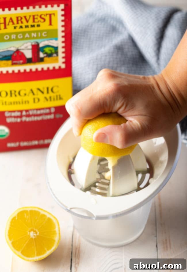 A hand juicing a fresh lemon to extract the juice for the buttermilk recipe.