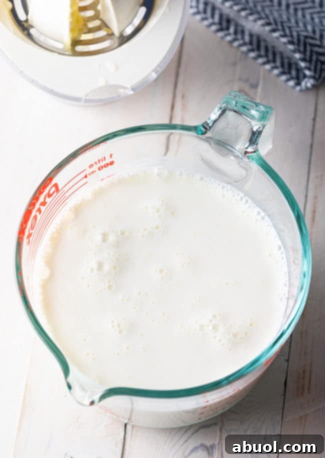 A glass measuring cup showing the buttermilk substitute in the process of curdling.