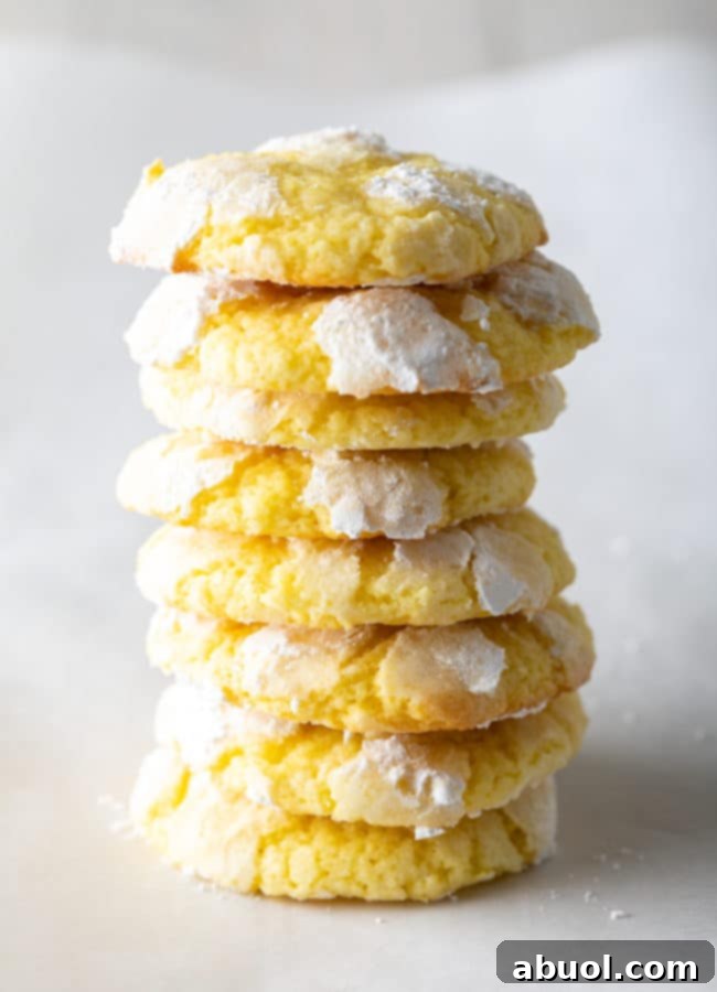 A tower of perfectly baked lemon crinkle cookies, showcasing their inviting texture and beautiful crackled powdered sugar coating.