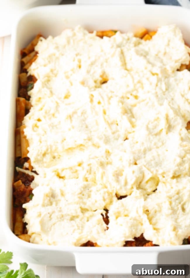 Cheesy Sausage Ziti Bake 2 Ricotta Filling layered on top of ziti in a baking dish for Baked Ziti with Sausage Recipe