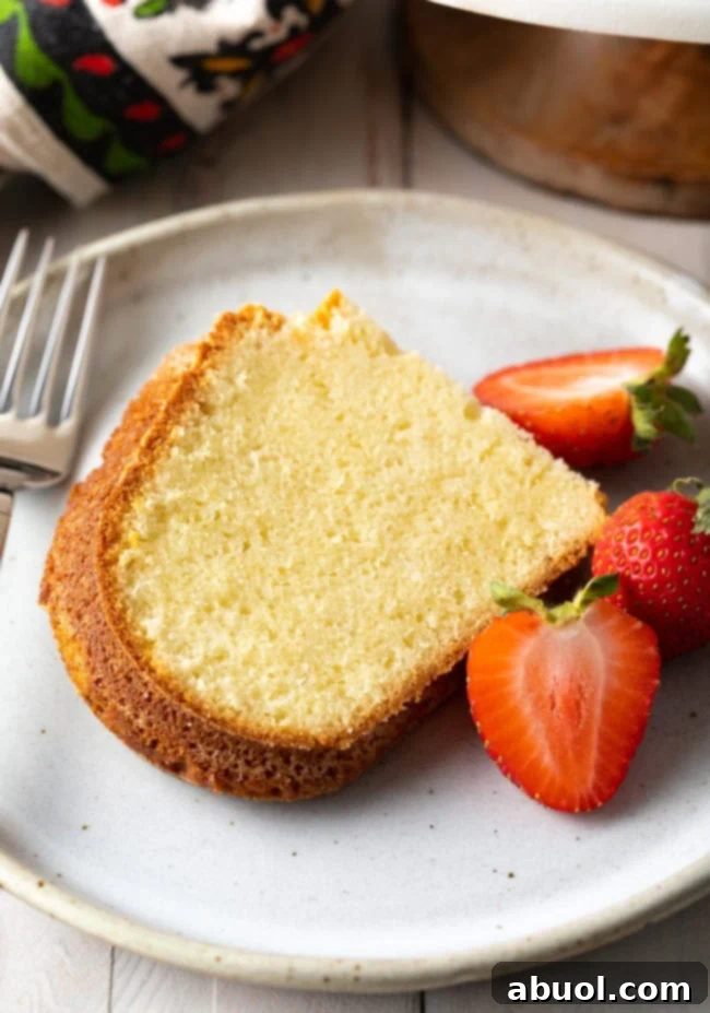 Side view of a single slice of cream cheese pound cake with a generous serving of fresh berries.