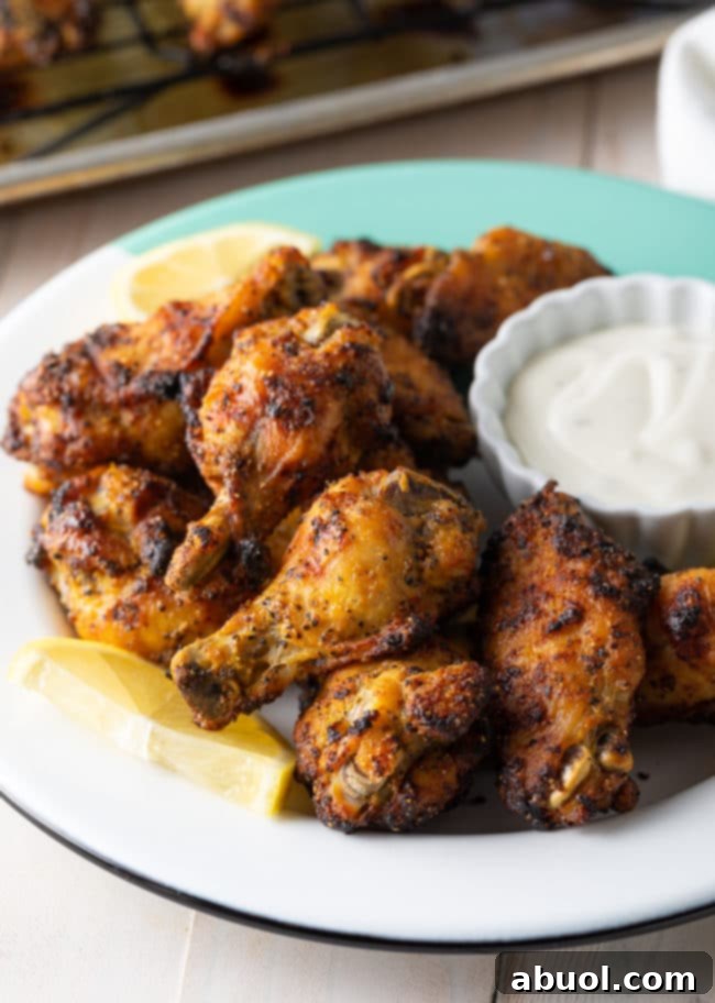Crispy Baked Lemon Pepper Wings 2 A plate of golden-brown, ultra-crispy baked lemon pepper chicken wings, garnished with fresh lemon wedges and parsley.