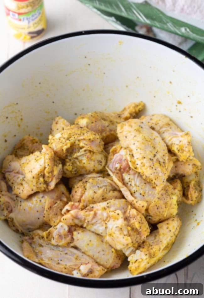 Crispy Baked Lemon Pepper Wings 10 Close-up of a single chicken wing heavily coated with lemon pepper rub.