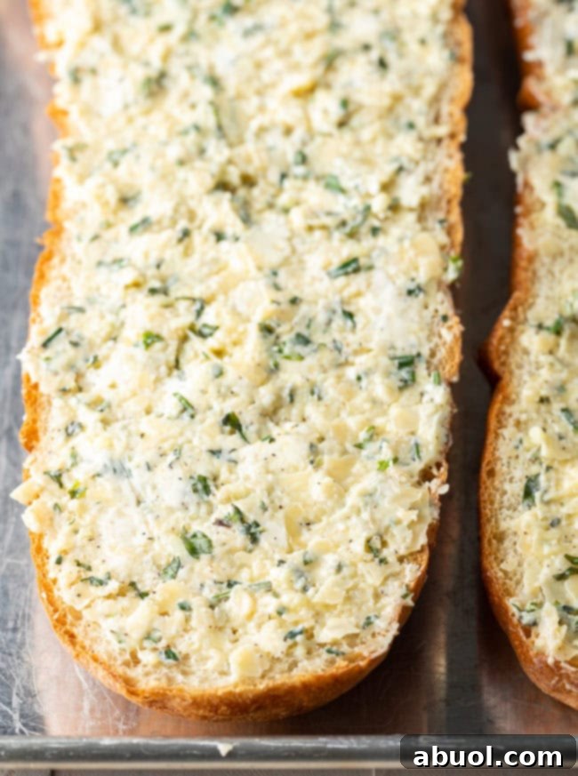 Two unbaked half loaves of bread covered with garlic bread seasoning.