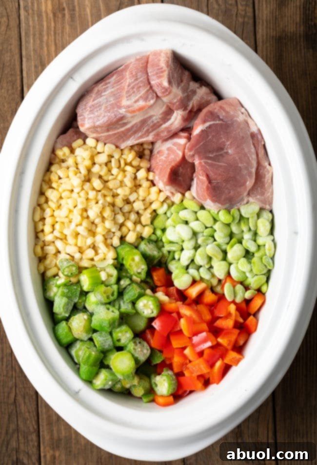 Set It and Forget It Brunswick Stew 5 Fresh ingredients, including chopped vegetables and raw pork roast, piled inside a slow cooker before cooking.