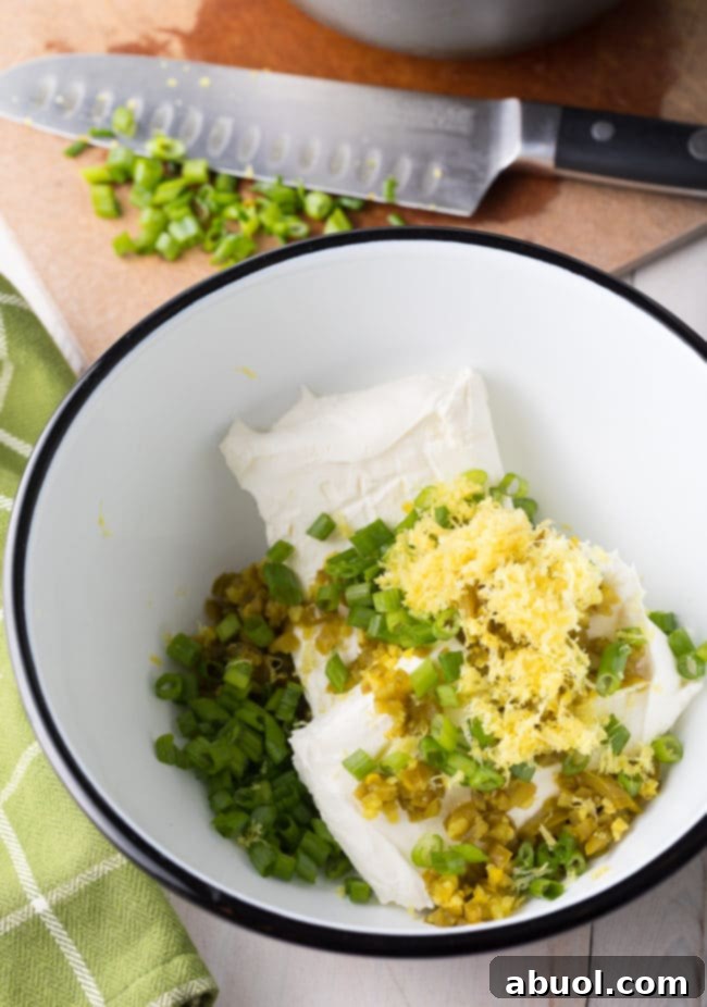 cream cheese in bowl with herbs and lemon zest