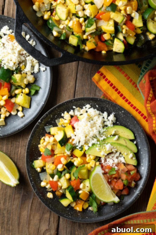 Calabacitas Recipe - Sauteed squash, zucchini and corn served on a plate with cheese, avocado and lime. 