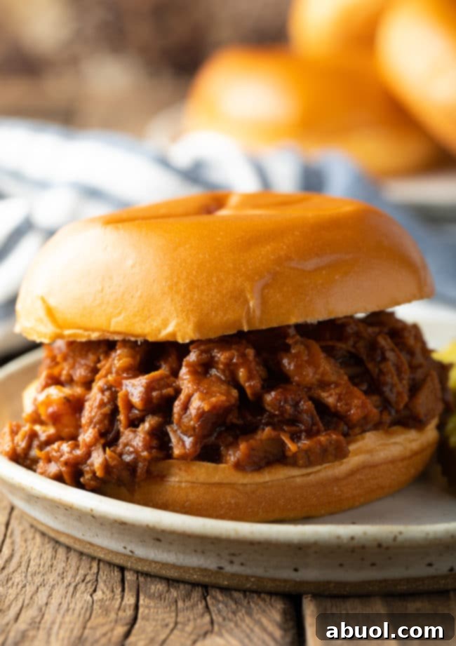 A mouth-watering BBQ brisket sandwich served on a plate, showcasing its rich, chopped beef filling and a soft bun.
