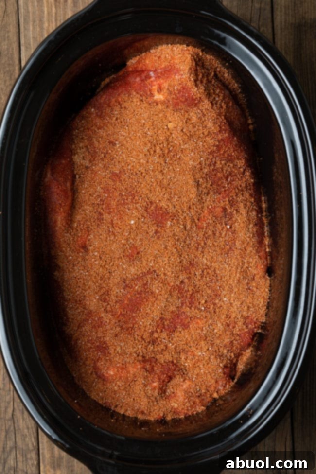 Raw beef brisket seasoned with dry rub, ready to be placed in a slow cooker.