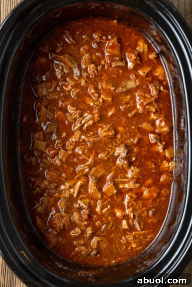 Close-up of saucy, chopped beef brisket simmering in the slow cooker, ready to be served.
