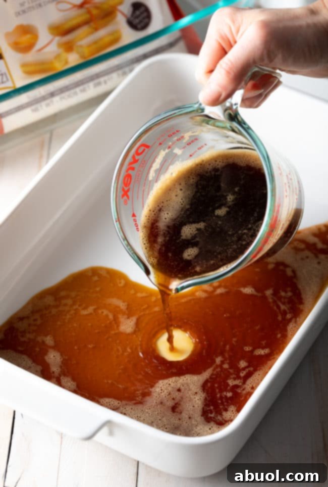 A hand carefully pours dark espresso into a shallow dish, preparing the flavorful liquid for dipping ladyfingers.