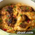 Authentic Cuban Arroz Con Pollo 11 Cuban Arroz Con Pollo Recipe in a pot with serving spoon.