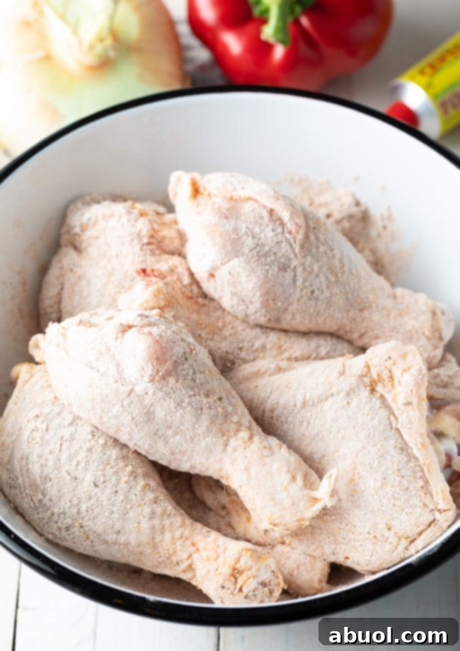 Authentic Cuban Arroz Con Pollo 5 Raw chicken pieces coated in flour and Sazon Completa, ready for browning in a dutch oven.