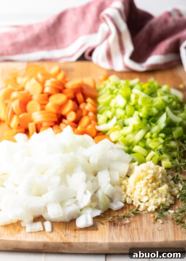 Chopped white onion, carrots, celery and garlic on a cutting board, prepared for chicken and rice. 
