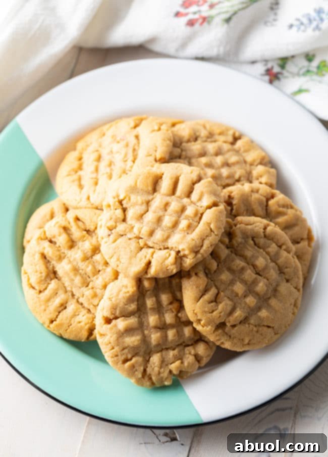Chewy Best Peanut Butter Cookies Recipe with Peanuts piled high on a green and white striped plate.