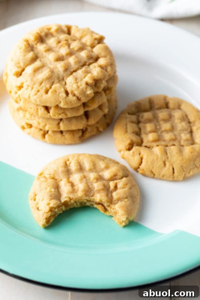 Irresistible golden-brown peanut butter cookies stacked on a plate in a close-up shot.