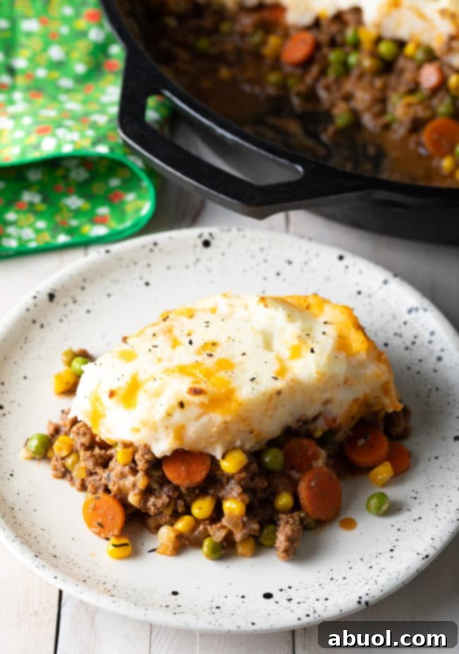 A delicious Irish Cottage Pie (beef) served on a plate with more of the pie visible in the background, inviting you to enjoy this hearty meal.