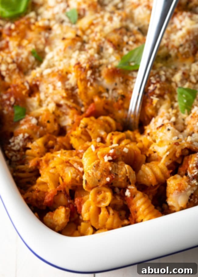Effortless No-Boil Chicken Parmesan Pasta 11 Large serving spoon taking a portion of baked chicken pasta from the baking dish.