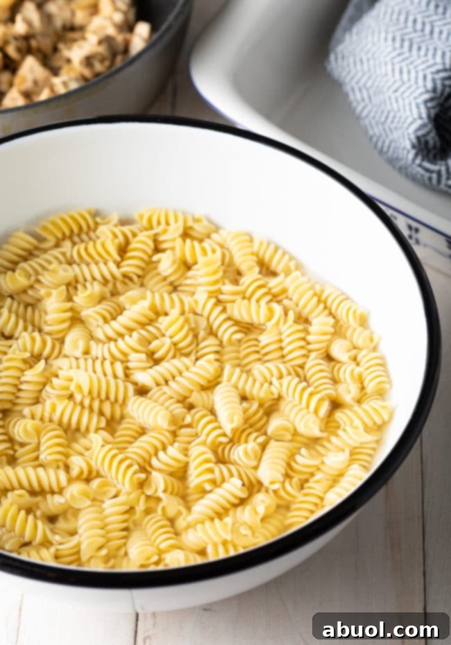 Effortless No-Boil Chicken Parmesan Pasta 5 Fusilli pasta in a large bowl soaking in hot water.