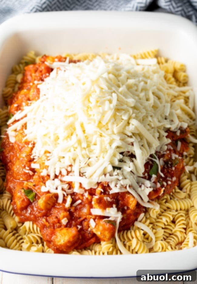 Effortless No-Boil Chicken Parmesan Pasta 8 Pasta in a baking dish topped with chicken pasta sauce mixture and shredded mozzarella cheese.