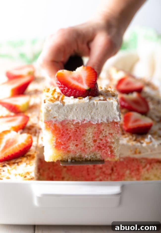 Easy Poke Cake lifted out of pan, showing its perfect shape and topping.