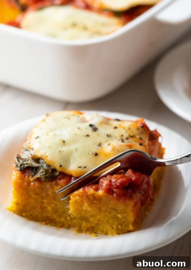 Close view, fork cutting into a square of margherita baked polenta on a white plate.