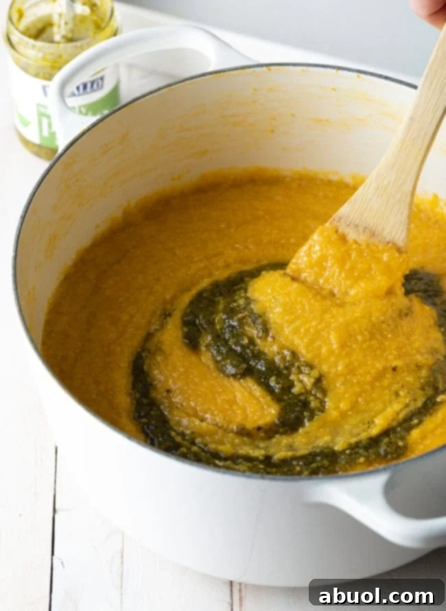 Stirring pesto into the polenta in a large pot on the stovetop.