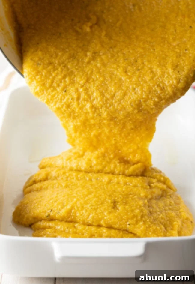 Pouring soft yellow polenta in a deep white baking dish.