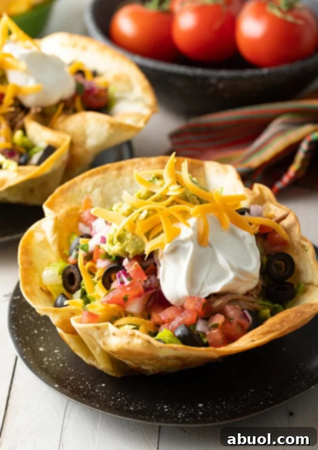Crispy Tortilla Bowls generously filled with colorful taco salad, presented beautifully on black plates, ready to be enjoyed.