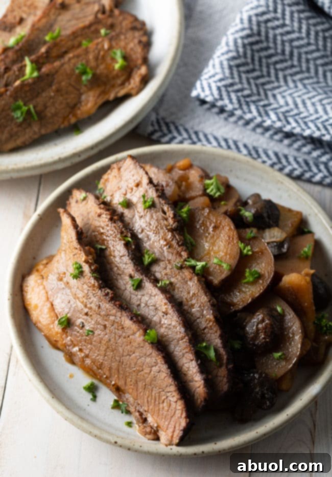 Crock pot beef brisket with potatoes and onions served on a platter