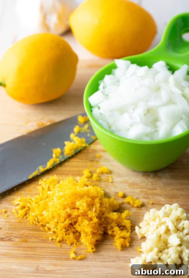 A bowl of fresh lemons, a sweet onion, and garlic cloves, ready for preparation.